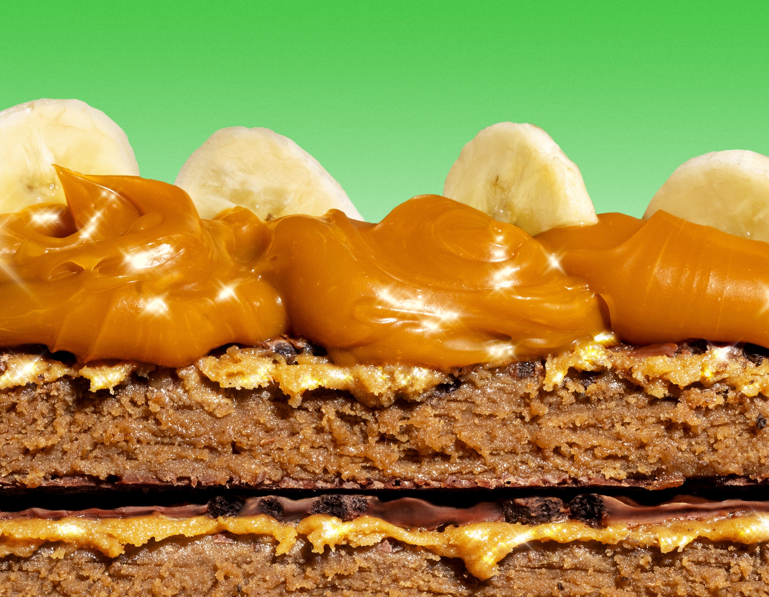 Close-up of a layered dessert with caramel and banana slices on a green background